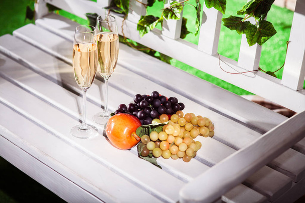 Romanttinen illallinen hedelmiä ja kaksi lasillista viiniä valkoisella
  - Valokuva, kuva