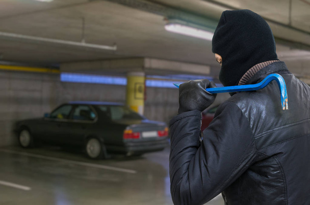 Ladrón con palanca va a robar coche del garaje
. - Foto, Imagen