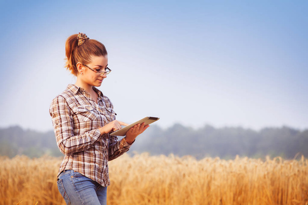 Pretty farmer girl in glasses keeps a crop accounting on the tab - Fotografie, Obrázek