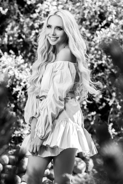 Black-white outdoor portrait of beautiful young blond woman in stylish dress. - Photo, image