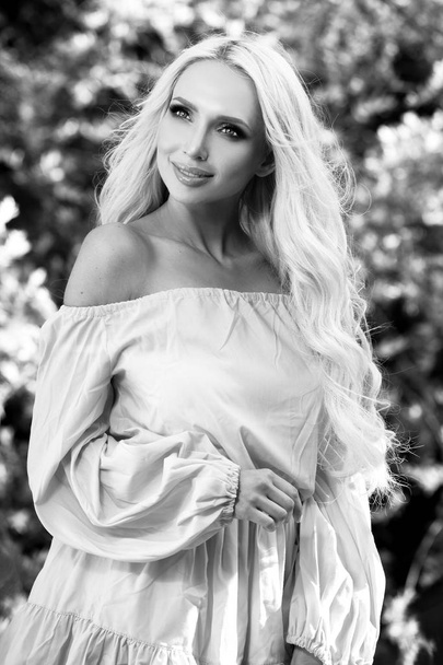 Retrato al aire libre blanco y negro de una hermosa mujer rubia joven en vestido elegante
. - Foto, imagen