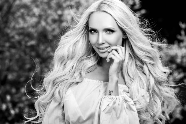 Black-white outdoor portrait of beautiful young blond woman in stylish dress. - Φωτογραφία, εικόνα
