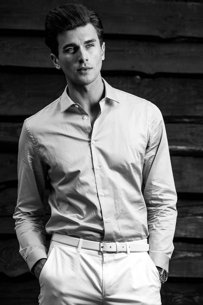 Black-white portrait of young handsome fashionable man against wooden wall. - Fotó, kép