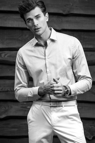 Black-white portrait of young handsome fashionable man against wooden wall. - 写真・画像