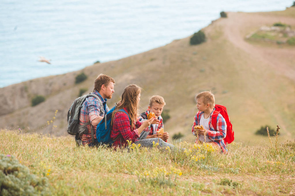 Family of four people eating fastfood in mountains - 写真・画像