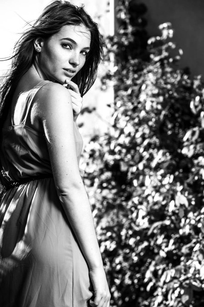 Black-white outdoor portrait of beautiful emotional young brunette woman in stylish dress - Фото, зображення