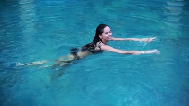 Glamoureuze brunette met tatoeage zwemt - Video