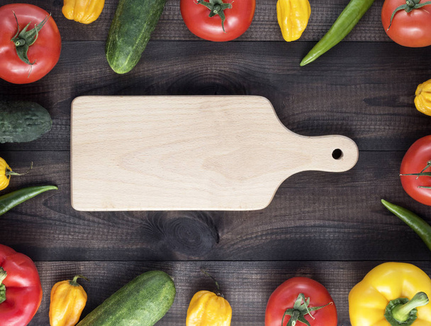 Cutting board and fresh vegetables on wooden table - Фото, зображення