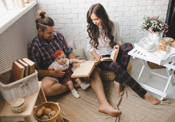 Young family reading story indoors - Foto, imagen