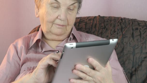 Elderly woman holding the silver tablet computer - Felvétel, videó