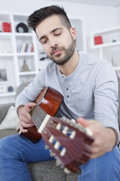 young man playing guitar at home - 写真・画像