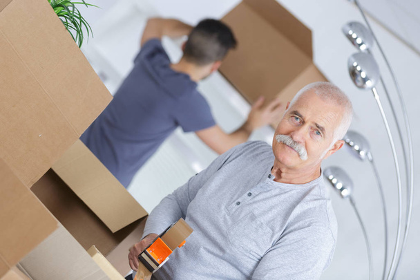 senior closing a cardboard box as he is moving houses - 写真・画像