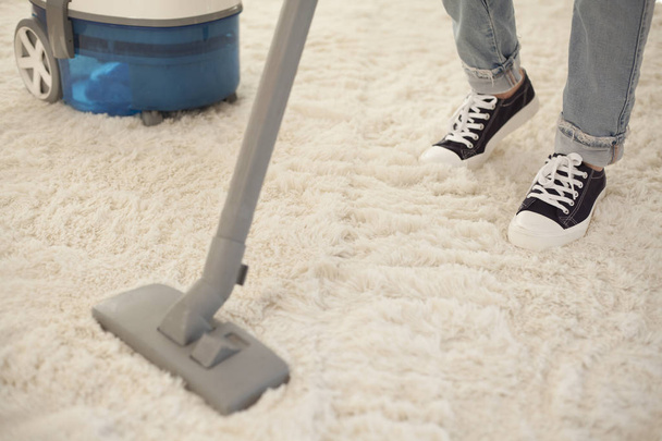 Woman cleaning carpet with a vacuum cleaner in room - Foto, Imagen