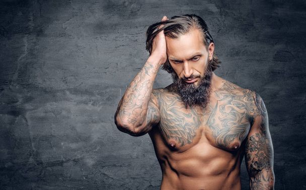 Бородатий чоловік з татуйованим м'язистим тілом
 - Фото, зображення