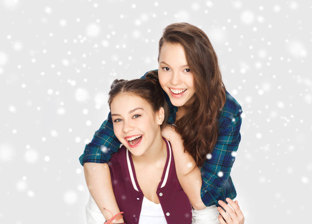 happy smiling teenage girls hugging over snow - 写真・画像