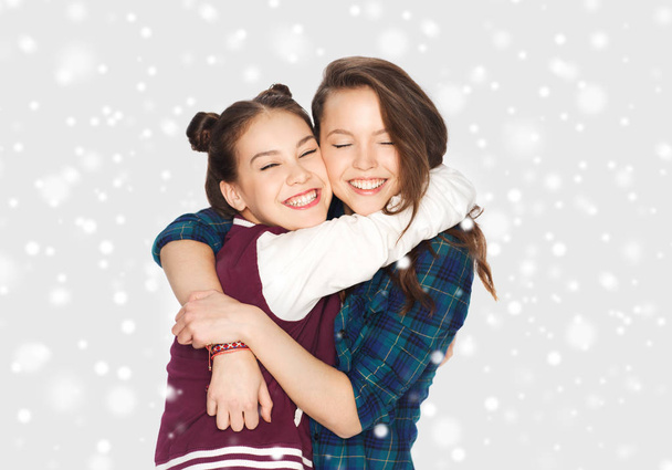 happy smiling teenage girls hugging over snow - 写真・画像
