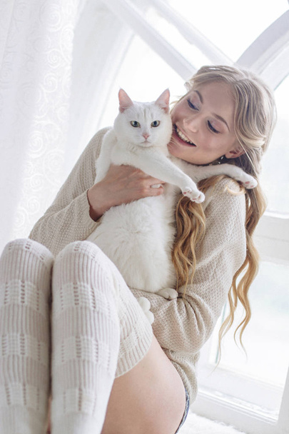 красива сексуальна блондинка сидить у вікні разом з кішкою
 - Фото, зображення