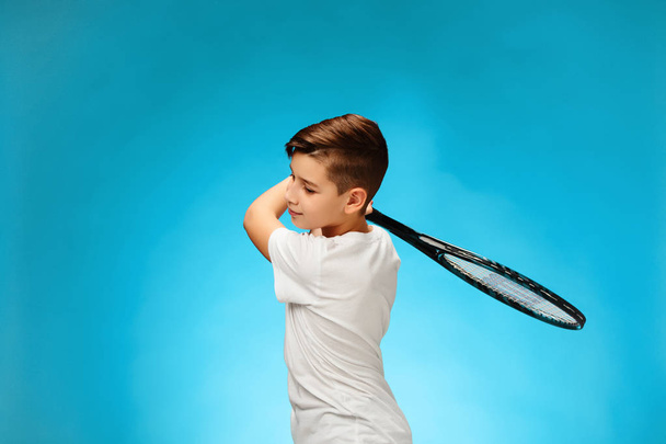 Young tennis player on blue background. - Valokuva, kuva