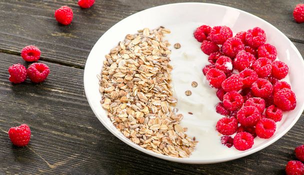 Muesli, yogurt and raspberries on a wooden background.  - 写真・画像