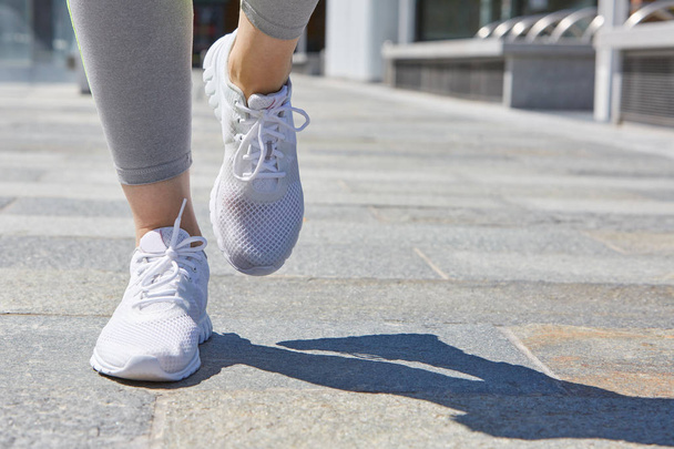 Woman running with white shoes outdoor in the city, sunny day - Foto, Bild