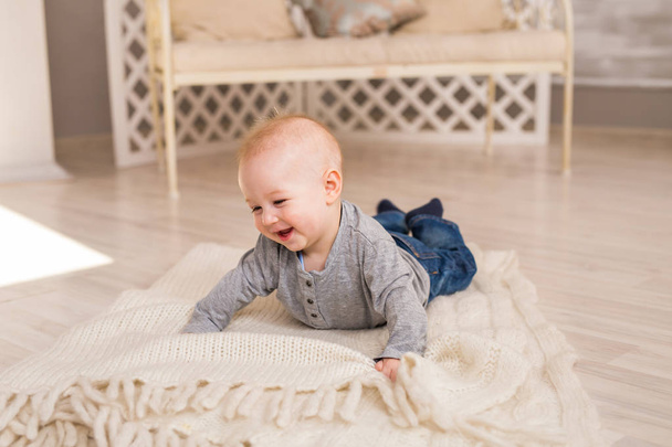Schattige lachende babyjongen in witte zonnige slaapkamer. Pasgeboren kind ontspannen. Familie ochtend thuis. - Foto, afbeelding