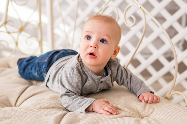 entzückender kleiner Junge im weißen, sonnigen Schlafzimmer. Neugeborenes entspannt sich. Familienmorgen zu Hause. - Foto, Bild