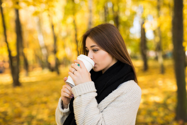 Młoda dziewczyna wypić kawę w jesień żółty słoneczny park - Zdjęcie, obraz