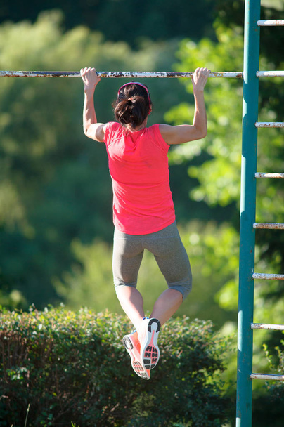 Strong woman athlete is Chin-ups and Pullups training on an aban - 写真・画像