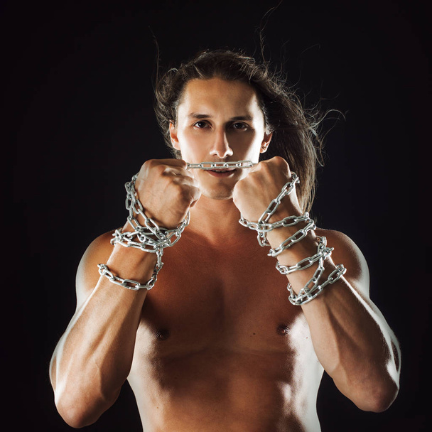 Young man with long hair breaks the iron chain. Strong. Concept of resistance - Photo, image