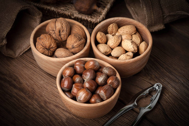 Walnuts, hazelnuts and almonds in-shell in wooden bowl. - Photo, Image