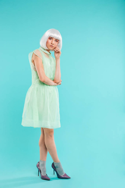 Fashionable young woman in blonde wig standing and posing - 写真・画像
