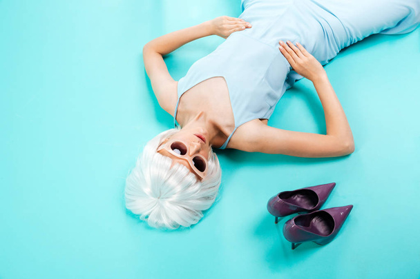 Top view of beautiful blonde woman lying near her shoes - 写真・画像