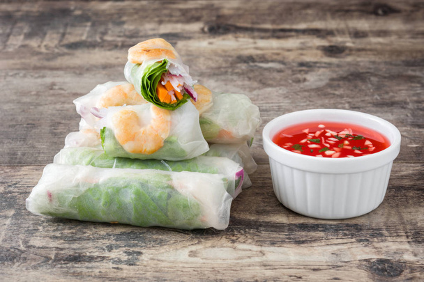 Вьетнамские роллы с овощами, рисовой лапшой и креветками на деревянном фоне
 - Фото, изображение