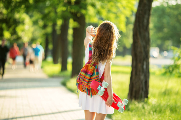 Chica sosteniendo un patín de plástico al aire libre
 - Foto, imagen
