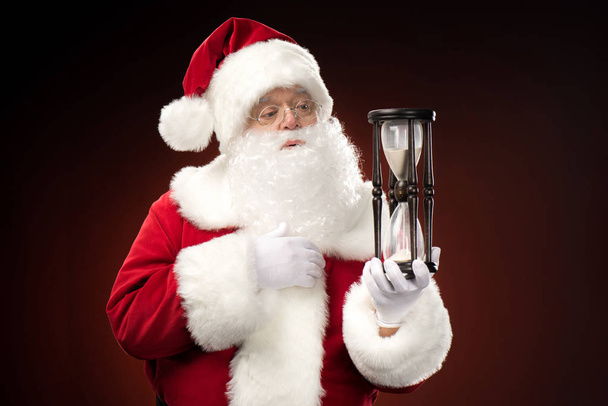 Santa Claus looking at hourglass   - Foto, Bild