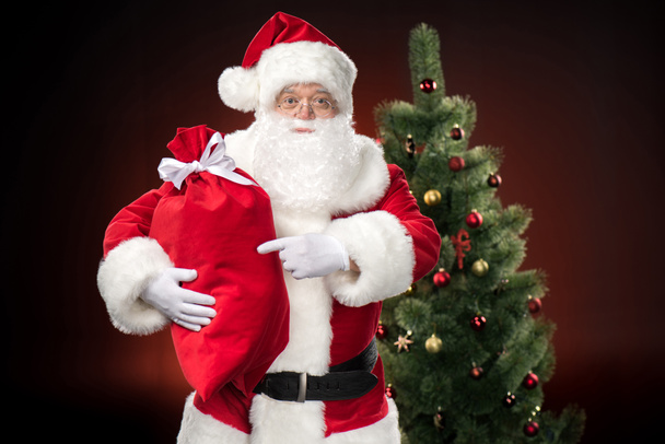 Santa Claus wijzend op zak - Foto, afbeelding