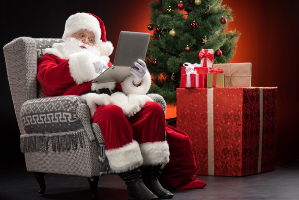 Santa Claus using laptop - Foto, afbeelding