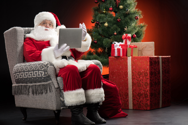 Joulupukki käyttää kannettavaa tietokonetta ja eleitä
 - Valokuva, kuva
