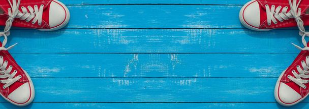 Banner con dos pares de zapatos juveniles rojos sobre una superficie de madera azul
 - Foto, Imagen