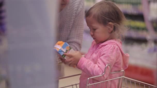 Woman with daughter picking fresh dairy products in refrigerated section - Footage, Video