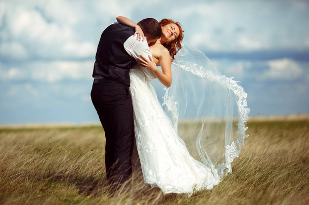 Groom kisses bride's chest while her veil flies away  - Fotó, kép