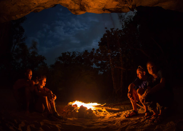 川の海岸に、夜のキャンプファイヤーの周り観光女の子のシルエット. - 写真・画像
