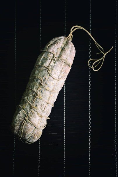 Italiaanse salami, gekruid zwarte achtergrond - Foto, afbeelding