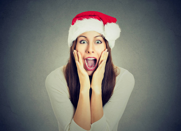 Surprised excited happy woman wearing red santa claus hat looking shocked  - Photo, Image