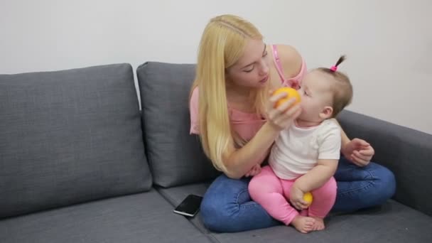 Mother with baby playing on couch - Materiał filmowy, wideo