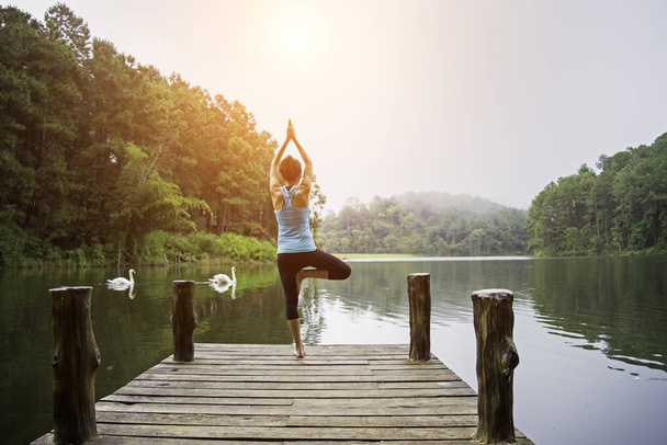 Young healthy woman practicing yoga on the bridge in the nature - Foto, imagen