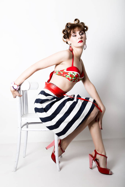 young beautiful woman sitting on a chair, pin-up style, girl styling hair with curlers - Fotoğraf, Görsel