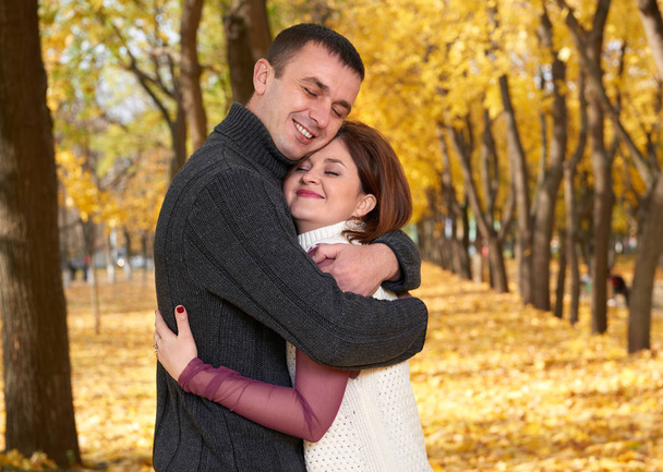 romantiků, šťastný dospělý pár objímat v podzimní městském parku, stromy s žluté listy, jasné slunce a šťastný emoce, něžnosti a pocity - Fotografie, Obrázek