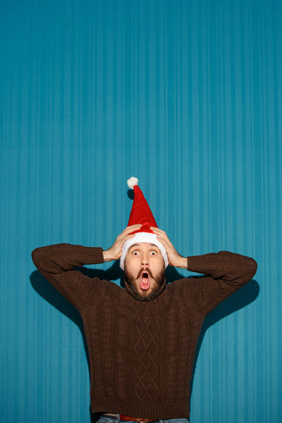 Surprised christmas man wearing a santa hat - Foto, Bild