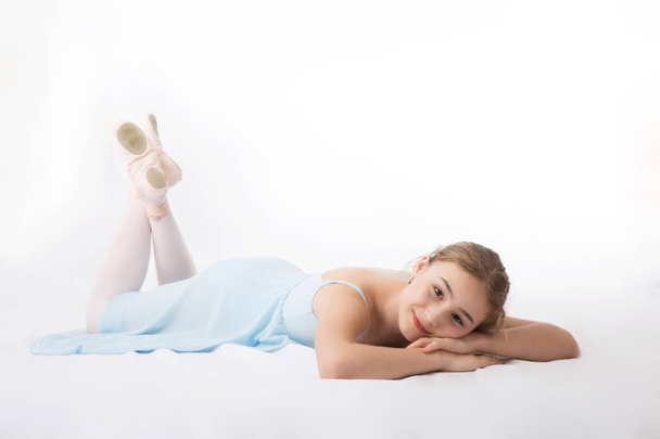Girl in blue dress resting on the floor on a white background - Фото, изображение